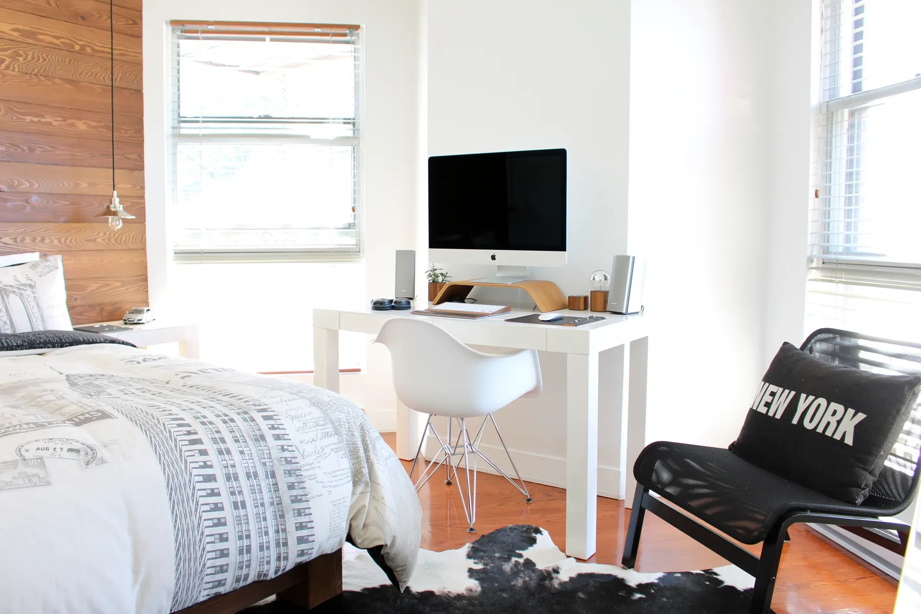 Bright bedroom with a desk by the window and a wood accent wall