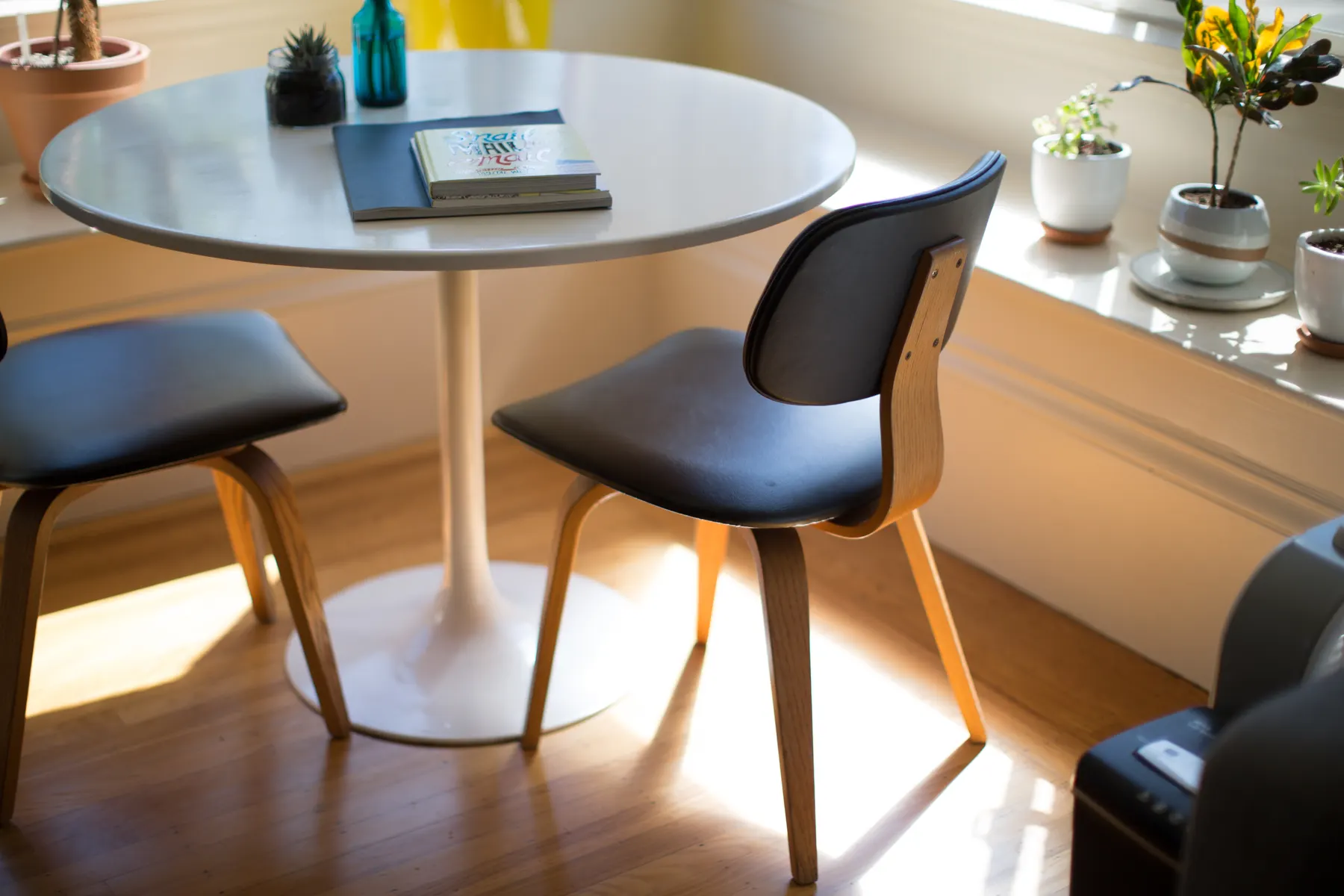 Round dining table with two chairs in a sunlit corner