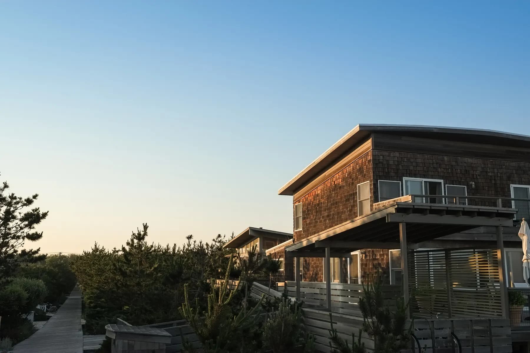Cedar shingled home with a deck, lit by low evening sun