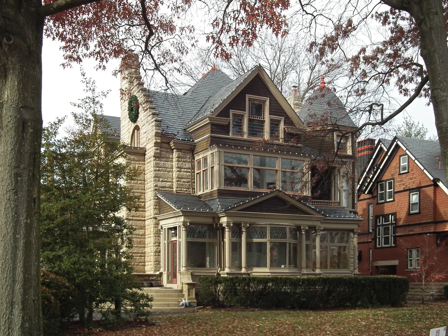 Stone and shingle home with a wreath on the chimney and a bay window