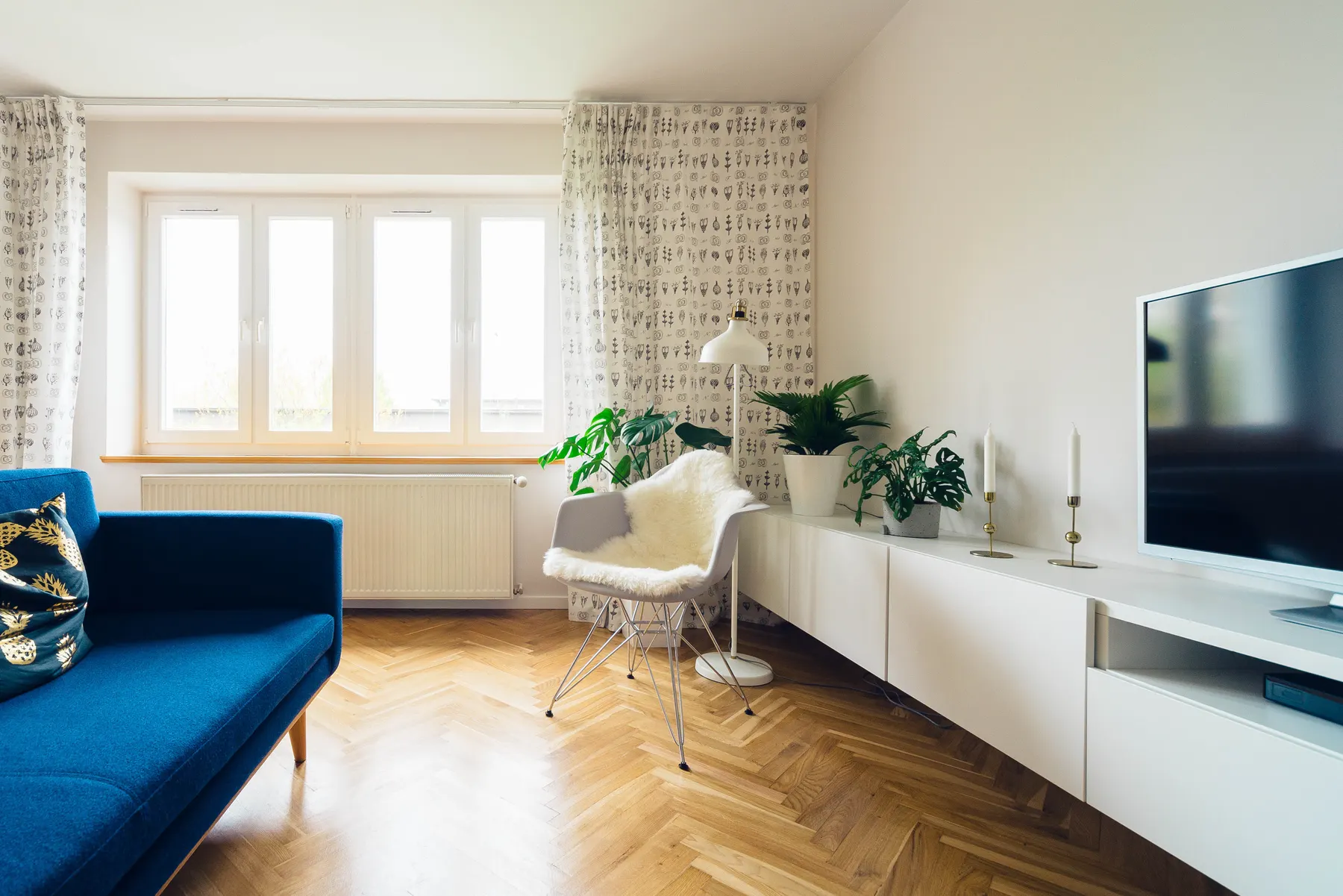 Living room with a blue sofa, herringbone floor and tall windows